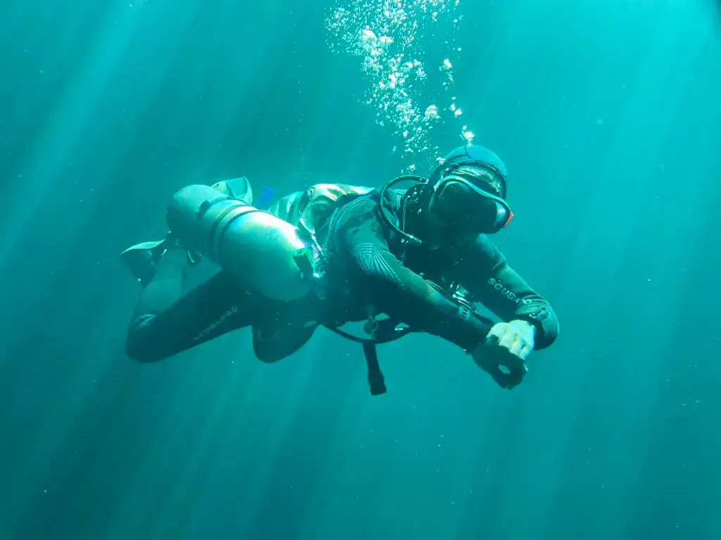 Diver silhouetted in light beams inside a cenote