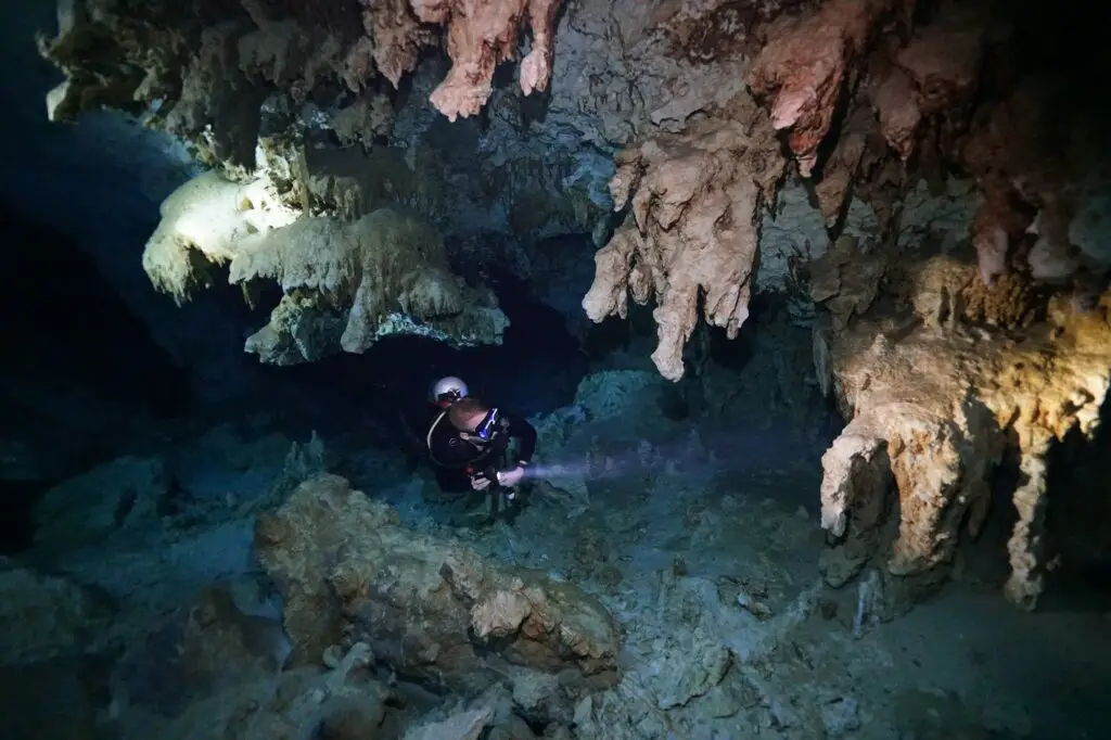 Diver passing stalactites in the cavern of Cenote Dos Ojos