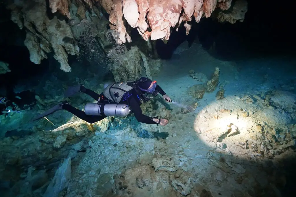 Diver with a dive light on the cavern line of Cenote Dos Ojos