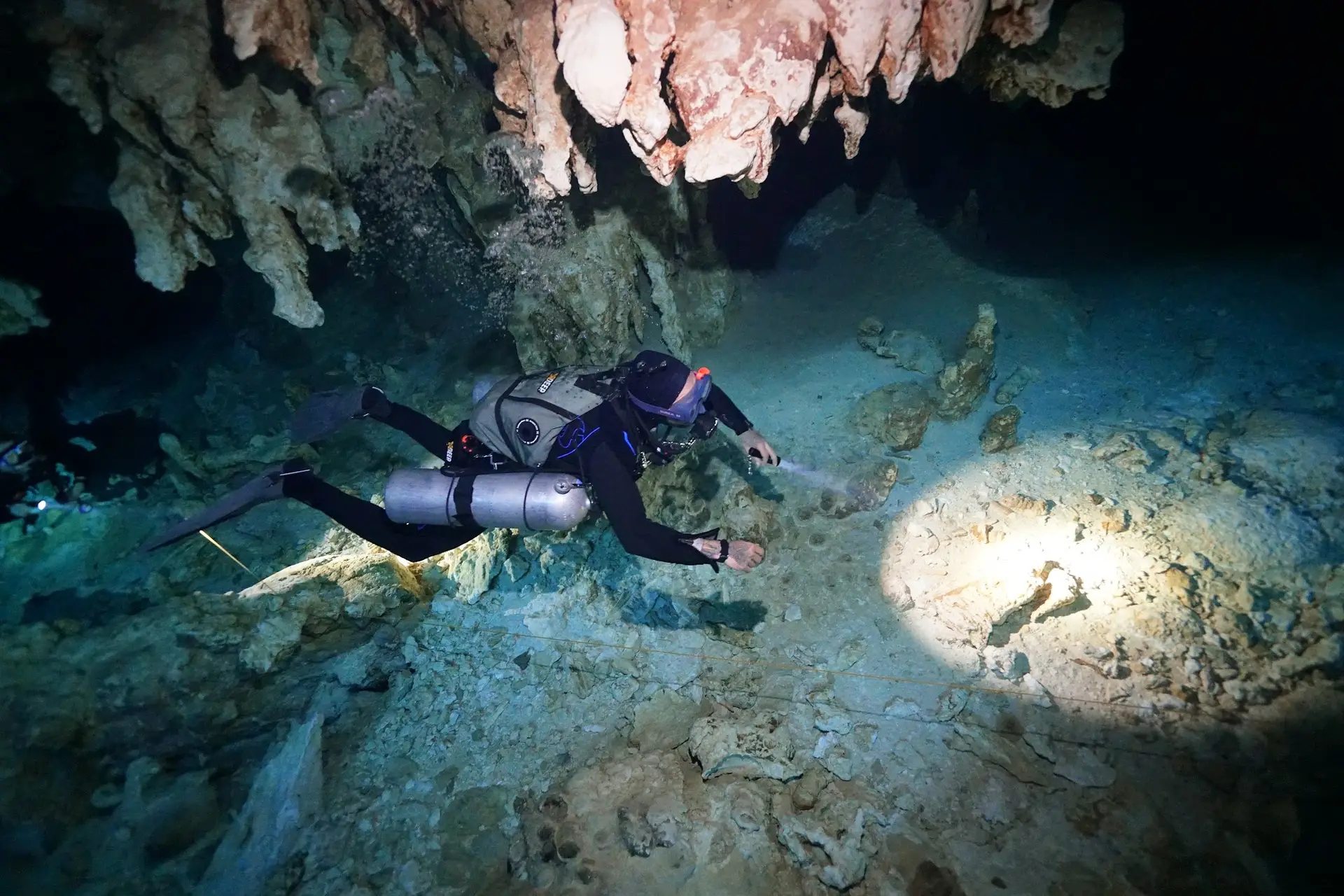 Diver with a dive light on the cavern line of Cenote Dos Ojos